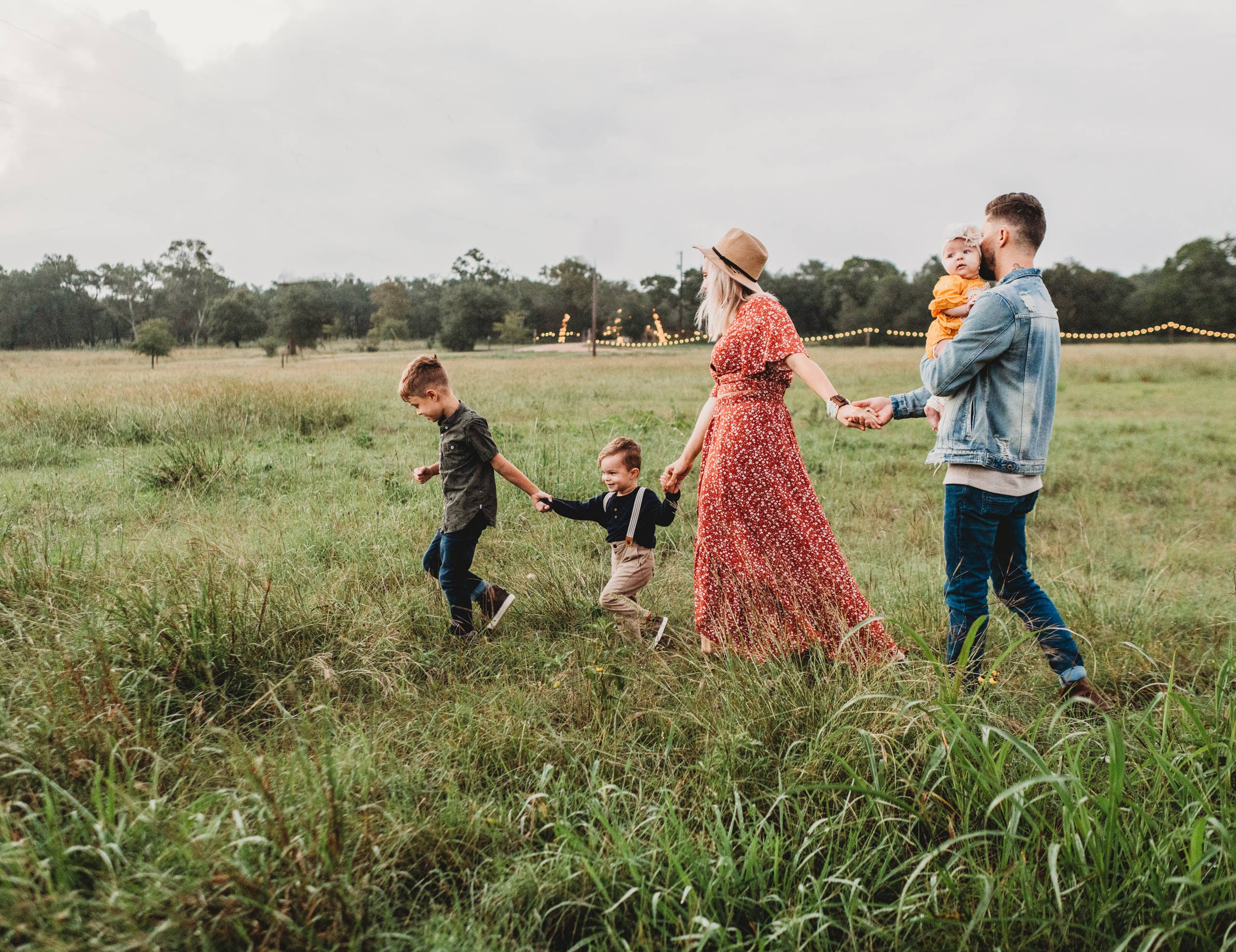 Family walking hand in hand across a grassy field together