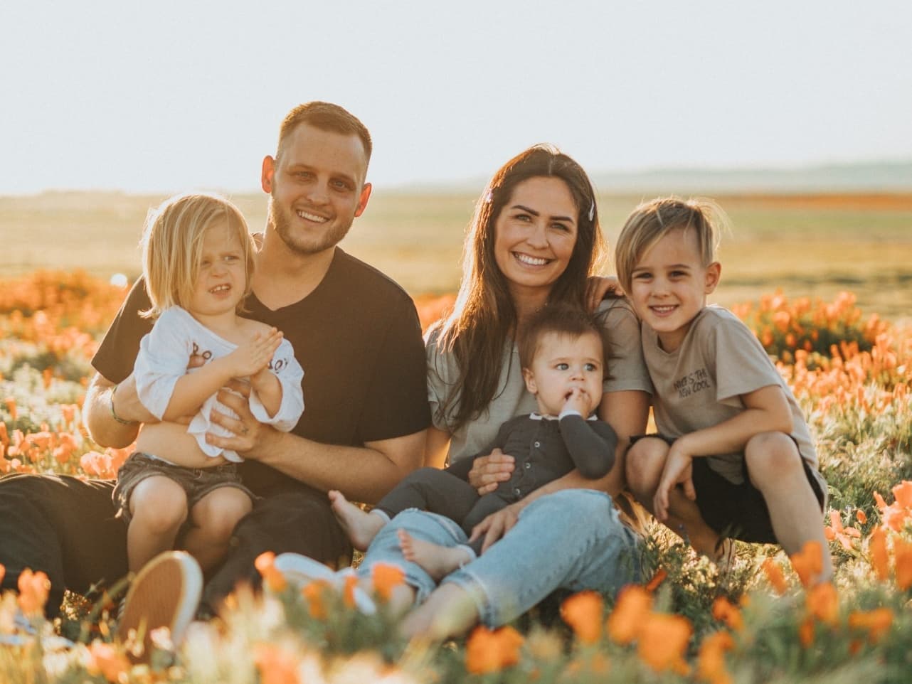 Family together in a California field of orange flowers at sunset
